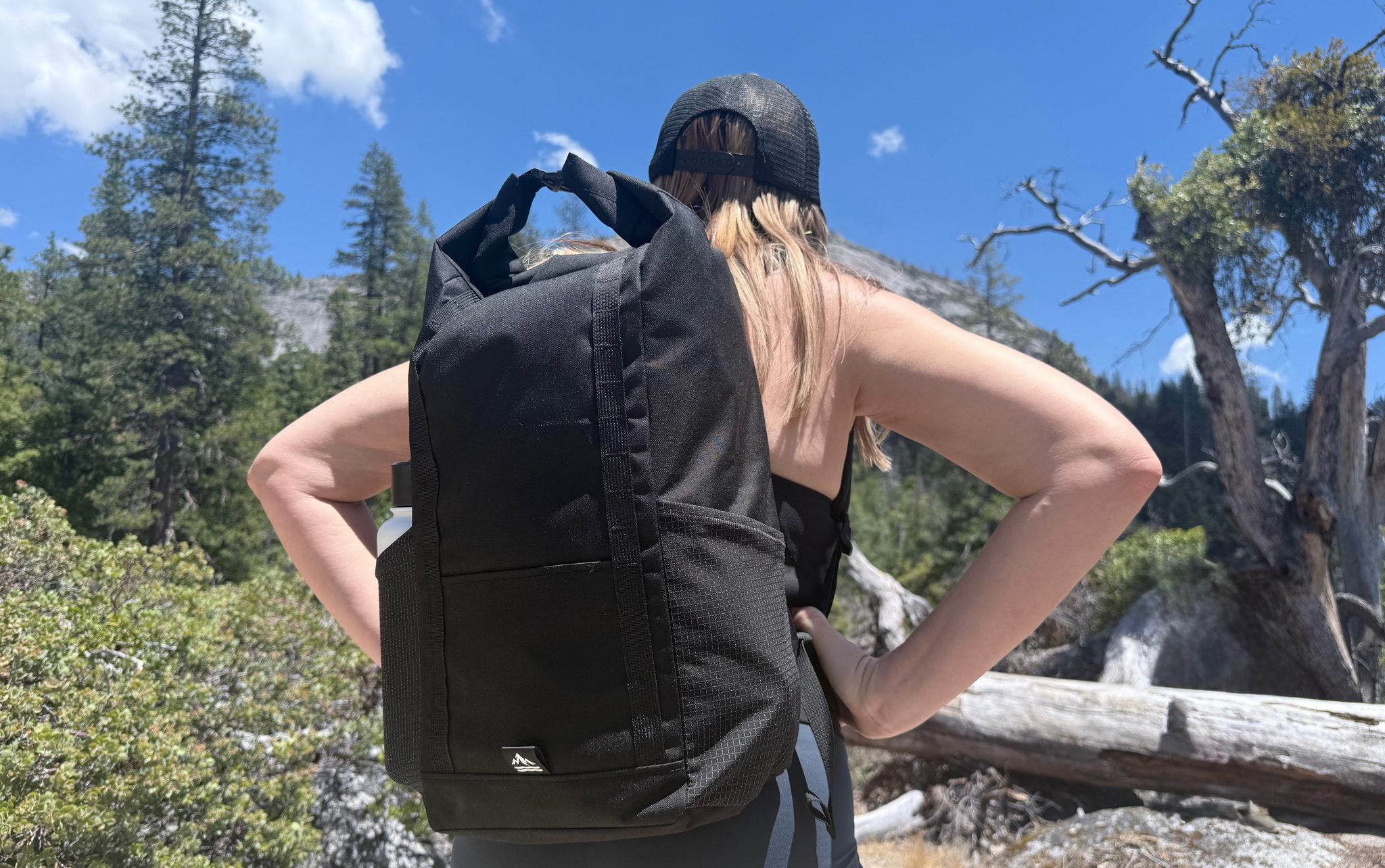 Rear view of the black 17L Rolltop Daypack being worn on a trail