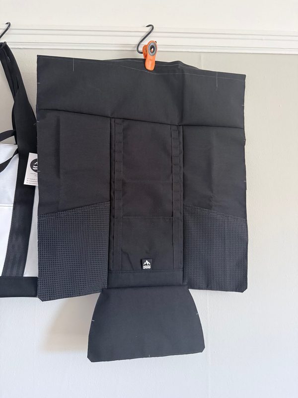 Front panel of the 17L Rolltop Daypack during construction, showing the exterior pocket and stretch-fabric water bottle pockets